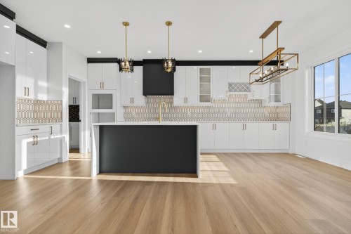 Two tone kitchen with modern cabinets, a center island with sink, light wood-style floors, backsplash, and light stone counters - 3508 6 Street, Edmonton, AB - Indoor Photo Showing Kitchen With Upgraded Kitchen
