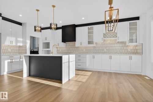 Kitchen featuring white cabinets, an island with sink, light wood finished floors, decorative backsplash, and suspended lighting - 3508 6 Street, Edmonton, AB - Indoor Photo Showing Kitchen With Upgraded Kitchen