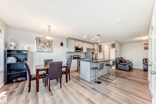 Kitchen featuring a kitchen island with sink, appliances with stainless steel finishes, open floor plan, a kitchen bar, and light wood finished floors - 1002 Stillwater Boulevard, Edmonton, AB - Indoor