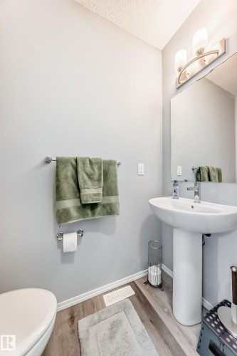 Half bathroom with light wood-type flooring and a textured ceiling - 1002 Stillwater Boulevard, Edmonton, AB - Indoor Photo Showing Bathroom