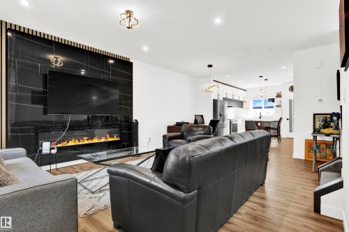 Living area featuring recessed lighting, light wood-type flooring, and a large fireplace - 9559 85 Street, Edmonton, AB - Indoor Photo Showing Living Room