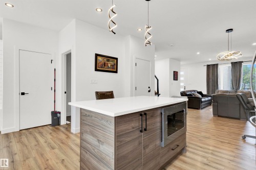 Kitchen featuring decorative light fixtures, recessed lighting, stainless steel microwave, light wood finished floors, and modern cabinets - 9559 85 Street, Edmonton, AB - Indoor