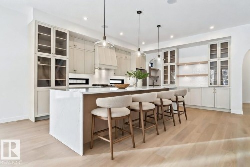 Kitchen with glass insert cabinets, a breakfast bar, hanging light fixtures, light wood-type flooring, and recessed lighting - 58 Redpoll Wynd, St. Albert, AB - Indoor Photo Showing Other Room
