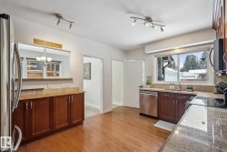Kitchen featuring stainless steel appliances, light wood-style flooring, tasteful backsplash, and light stone countertops - 
