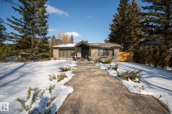 View of front facade featuring a chimney and driveway - 