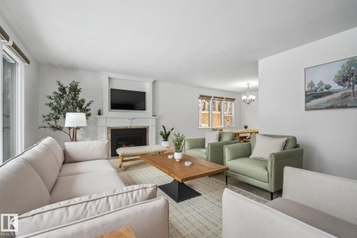 Living room with a warm lit fireplace and suspended lighting - 14018 100 Avenue, Edmonton, AB - Indoor Photo Showing Living Room With Fireplace
