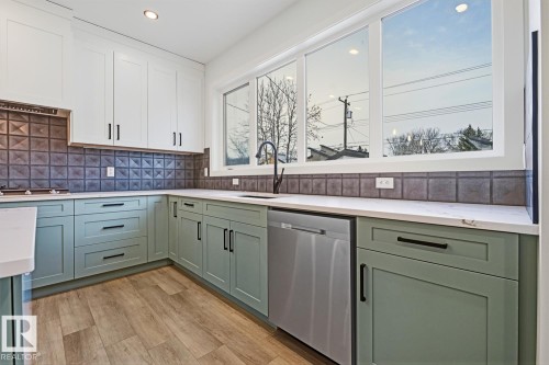 Two tone kitchen with stainless steel appliances, two tone cabinets, light wood-type flooring, decorative backsplash, and light stone counters - 9627 152 Street Nw, Edmonton, AB - Indoor Photo Showing Kitchen With Upgraded Kitchen