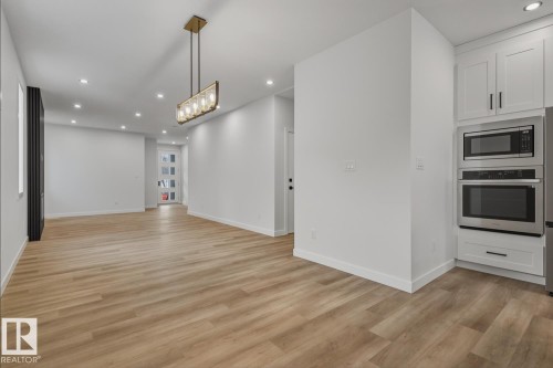 Kitchen featuring white cabinets, stainless steel appliances, light wood-style floors, and open floor plan - 9627 152 Street Nw, Edmonton, AB - Indoor