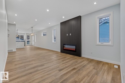 Unfurnished living room with light wood-style floors, a fireplace, and hanging lights - 9627 152 Street Nw, Edmonton, AB - Indoor Photo Showing Other Room