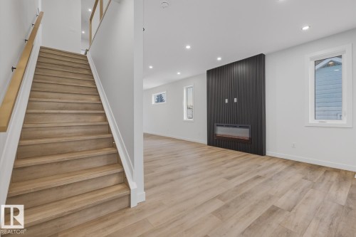 Staircase featuring wood finished floors, recessed lighting, and a large fireplace - 9627 152 Street Nw, Edmonton, AB - Indoor Photo Showing Other Room