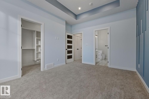 Unfurnished bedroom featuring a tray ceiling, a walk in closet, light carpet, recessed lighting, and ensuite bathroom - 9627 152 Street Nw, Edmonton, AB - Indoor Photo Showing Other Room