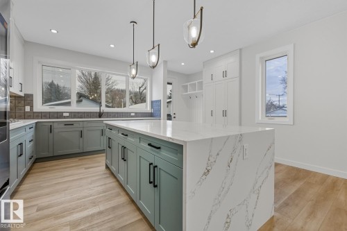 Kitchen with tasteful backsplash, a center island, light wood finished floors, light stone counters, and dual tone cabinetry - 9627 152 Street Nw, Edmonton, AB - Indoor Photo Showing Kitchen With Upgraded Kitchen