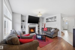 Living area with hardwood / wood-style floors, built in shelves, and a warm lit fireplace - 