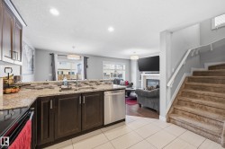Kitchen featuring a peninsula, dark wood finish cabinets, electric stove, light stone counters, and a textured ceiling - 