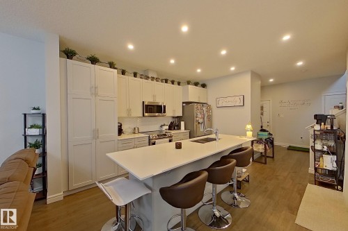 Kitchen with light wood-type flooring, white cabinetry, a kitchen island with sink, stainless steel appliances, and recessed lighting - 4419 Kinsella Green, Edmonton, AB - Indoor