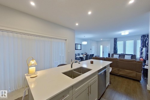 Kitchen with white cabinets, recessed lighting, open floor plan, an island with sink, and stainless steel dishwasher - 4419 Kinsella Green, Edmonton, AB - Indoor Photo Showing Kitchen With Double Sink