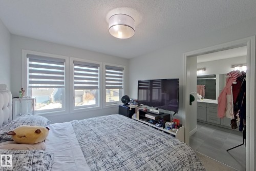 Bedroom with a textured ceiling and connected bathroom - 4419 Kinsella Green, Edmonton, AB - Indoor Photo Showing Bedroom