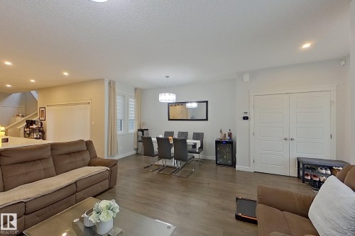 Living area featuring recessed lighting, wood finished floors, stairway, beverage cooler, and a textured ceiling - 4419 Kinsella Green, Edmonton, AB - Indoor Photo Showing Living Room
