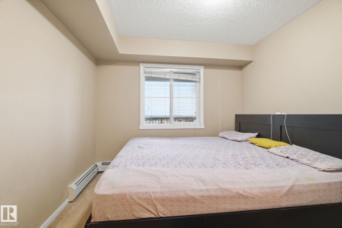 Carpeted bedroom with a textured ceiling and baseboards - 424 1510 Watt Drive, Edmonton, AB - Indoor Photo Showing Bedroom