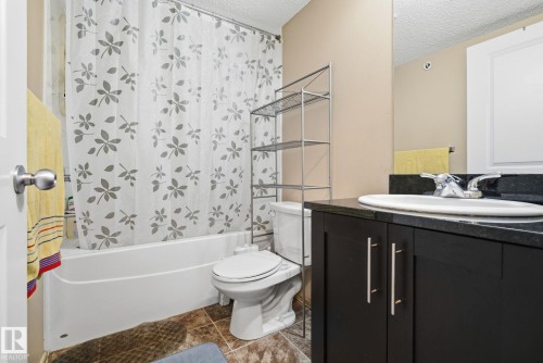 Bathroom featuring shower / bath combination with curtain, vanity, and a textured ceiling - 424 1510 Watt Drive, Edmonton, AB - Indoor Photo Showing Bathroom