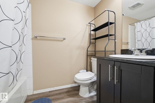 Bathroom featuring vanity, wood finished floors, a textured ceiling, and shower / tub combo with curtain - 424 1510 Watt Drive, Edmonton, AB - Indoor Photo Showing Bathroom