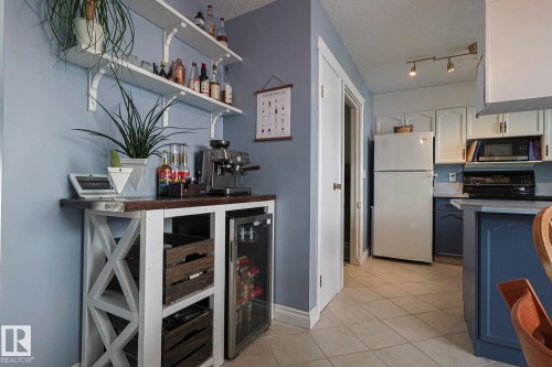Indoor dry bar featuring open shelves, two tone color scheme, freestanding refrigerator, wine cooler, and light tile patterned floors - 192 Dunluce Road, Edmonton, AB - Indoor Photo Showing Kitchen