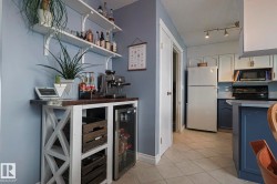Indoor dry bar featuring open shelves, two tone color scheme, freestanding refrigerator, wine cooler, and light tile patterned floors - 