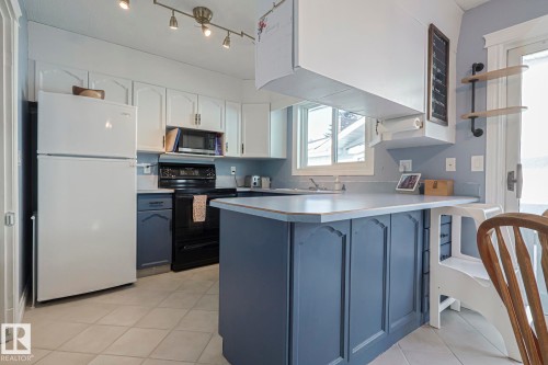 Kitchen featuring open shelves, two tone cabinetry, freestanding refrigerator, a peninsula, and black range with electric cooktop - 192 Dunluce Road, Edmonton, AB - Indoor Photo Showing Kitchen