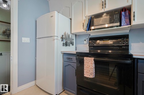 Kitchen featuring black electric range, light countertops, freestanding refrigerator, white cabinets, and light tile patterned flooring - 192 Dunluce Road, Edmonton, AB - Indoor Photo Showing Kitchen