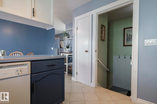 Kitchen featuring white dishwasher, a textured ceiling, light tile patterned floors, light countertops, and white cabinets - 192 Dunluce Road, Edmonton, AB - Indoor Photo Showing Other Room