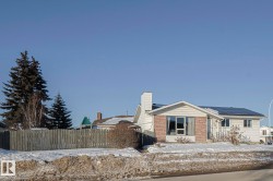 Ranch-style home with a chimney, brick siding, and solar panels - 