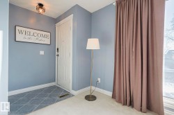 Foyer entrance featuring baseboards and dark carpet - 