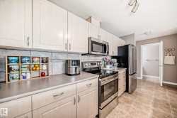 Kitchen with stainless steel appliances, light countertops, tasteful backsplash, and light tile patterned floors - 