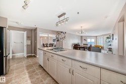 Kitchen featuring stainless steel appliances, open floor plan, light countertops, light tile patterned floors, and a chandelier - 