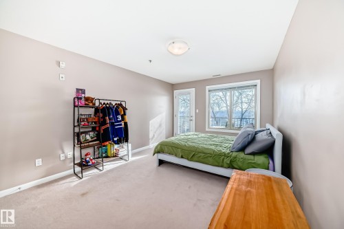 Carpeted bedroom featuring baseboards and access to exterior - 232 530 Hooke Road, Edmonton, AB - Indoor Photo Showing Bedroom
