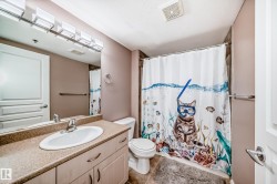Full bath featuring curtained shower, vanity, light tile patterned flooring, and a textured ceiling - 