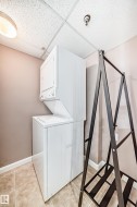 Laundry area featuring stacked washing machine and dryer and a drop ceiling - 