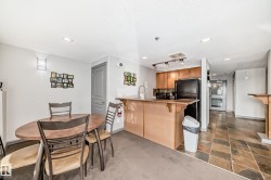 Kitchen with a kitchen breakfast bar, a peninsula, black appliances, wood finish cabinetry, and recessed lighting - 