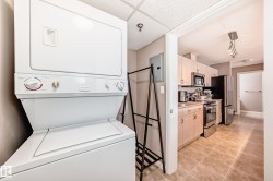 Laundry area featuring electric panel, stacked washing machine and dryer, and light tile patterned floors - 