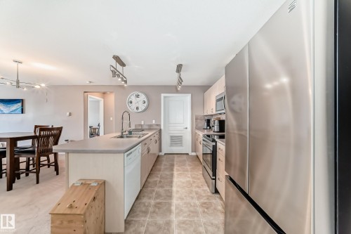 Kitchen with stainless steel appliances, a peninsula, light countertops, and decorative light fixtures - 232 530 Hooke Road, Edmonton, AB - Indoor Photo Showing Kitchen With Stainless Steel Kitchen