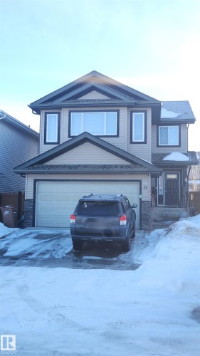 View of front of property featuring an attached garage, driveway, and stone siding - 31 Newgate Way, St. Albert, AB - Outdoor