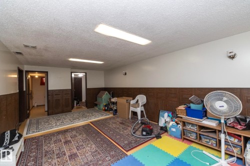 Rec room featuring a wainscoted wall, a textured ceiling, and wooden walls - 9020 152 Avenue, Edmonton, AB - Indoor Photo Showing Other Room