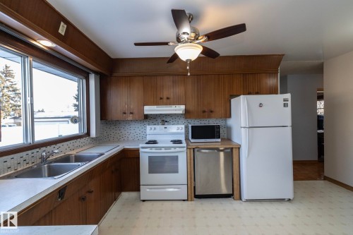 Kitchen featuring light flooring, white appliances, tasteful backsplash, a ceiling fan, and light countertops - 9020 152 Avenue, Edmonton, AB - Indoor Photo Showing Kitchen With Double Sink