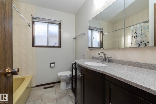 Full bath with vanity, plenty of natural light, light tile patterned floors, and shower / bathtub combination with curtain - 9020 152 Avenue, Edmonton, AB - Indoor Photo Showing Bathroom