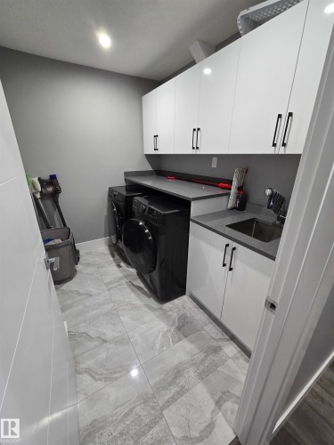 Laundry room featuring washer and clothes dryer, light marble finish floors, cabinet space, and recessed lighting - 1641 Enright Way Nw, Edmonton, AB - Indoor