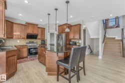 Kitchen with a kitchen island, brown cabinets, a kitchen breakfast bar, decorative backsplash, and appliances with stainless steel finishes - 