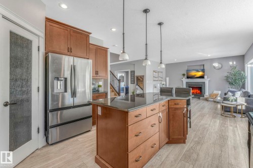 Kitchen with brown cabinets, stainless steel fridge, a kitchen island, pendant lighting, and light wood-style flooring - 2307 Rutherford Way, Edmonton, AB - Indoor Photo Showing Kitchen