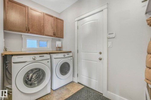 Laundry area featuring independent washer and dryer, stone finish flooring, and cabinet space - 2307 Rutherford Way, Edmonton, AB - Indoor Photo Showing Laundry Room