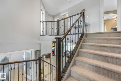 Stairway featuring arched walkways and a warm lit fireplace - 2307 Rutherford Way, Edmonton, AB - Indoor Photo Showing Other Room