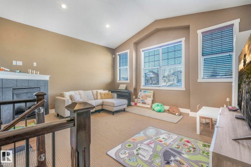 Living room featuring carpet floors, a tiled fireplace, vaulted ceiling, and recessed lighting - 2307 Rutherford Way, Edmonton, AB - Indoor